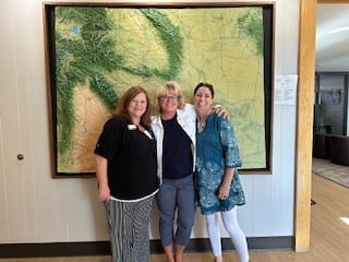 Three women from the Wyoming Business Council stand together, smiling