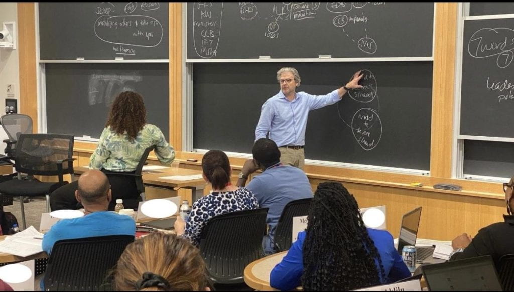 Matt Andrews teaching and pointing to the blackboard