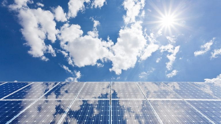 Solar panels with sky and clouds in background