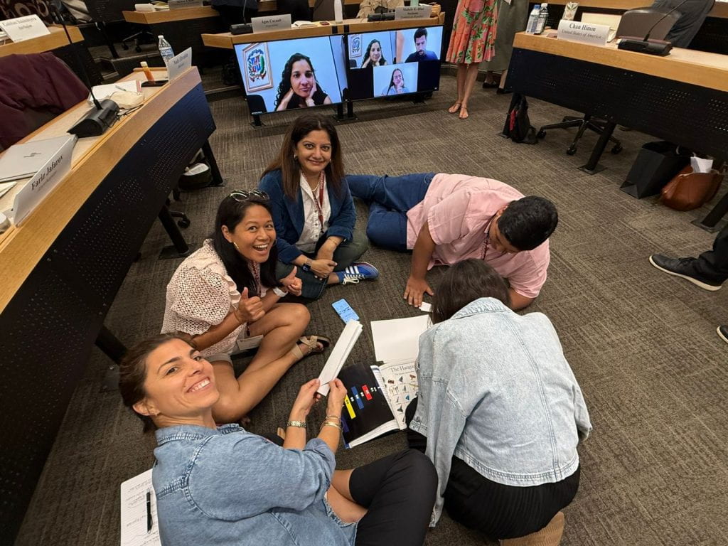Participants smiling on the floor while building paper airplanes for a classroom exercise