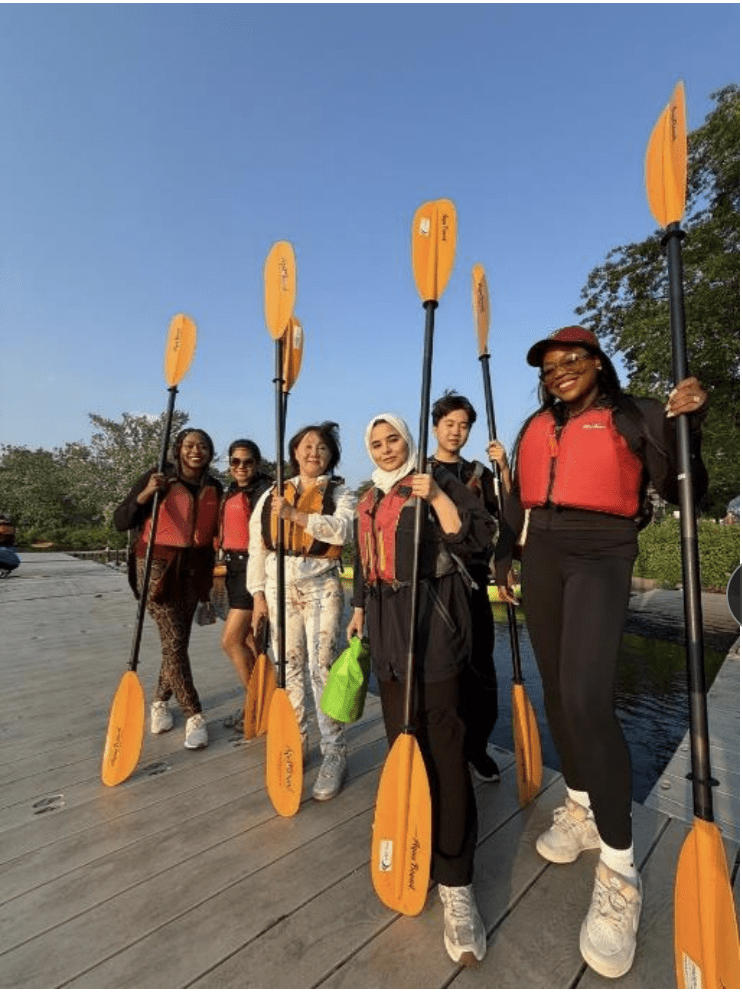 A group photo of IPP '25 alums with kayak paddles.