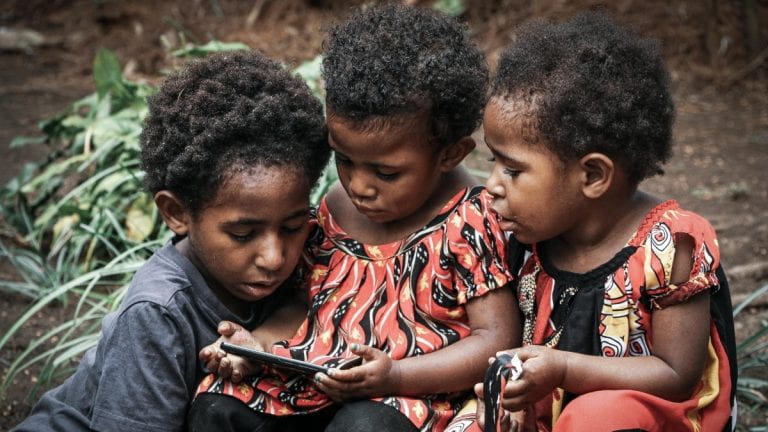 Children in Papua New Guinea looking at a phone