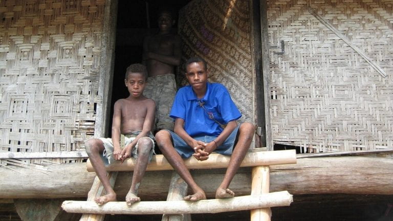 Kids in Papua New Guinea sitting on the steps of a hut