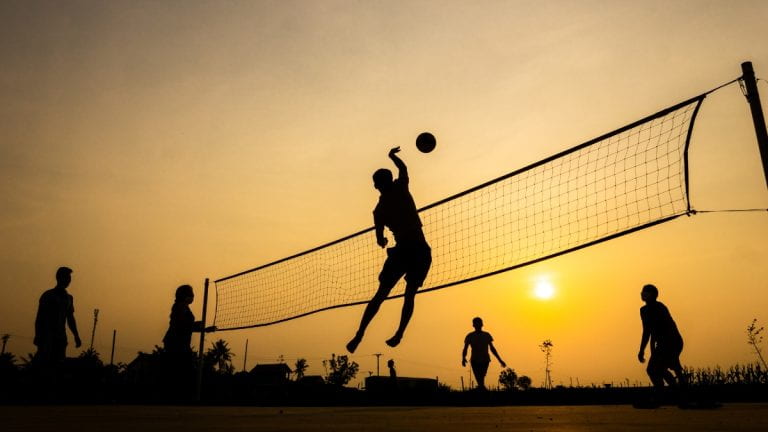 People playing volleyball at sunset